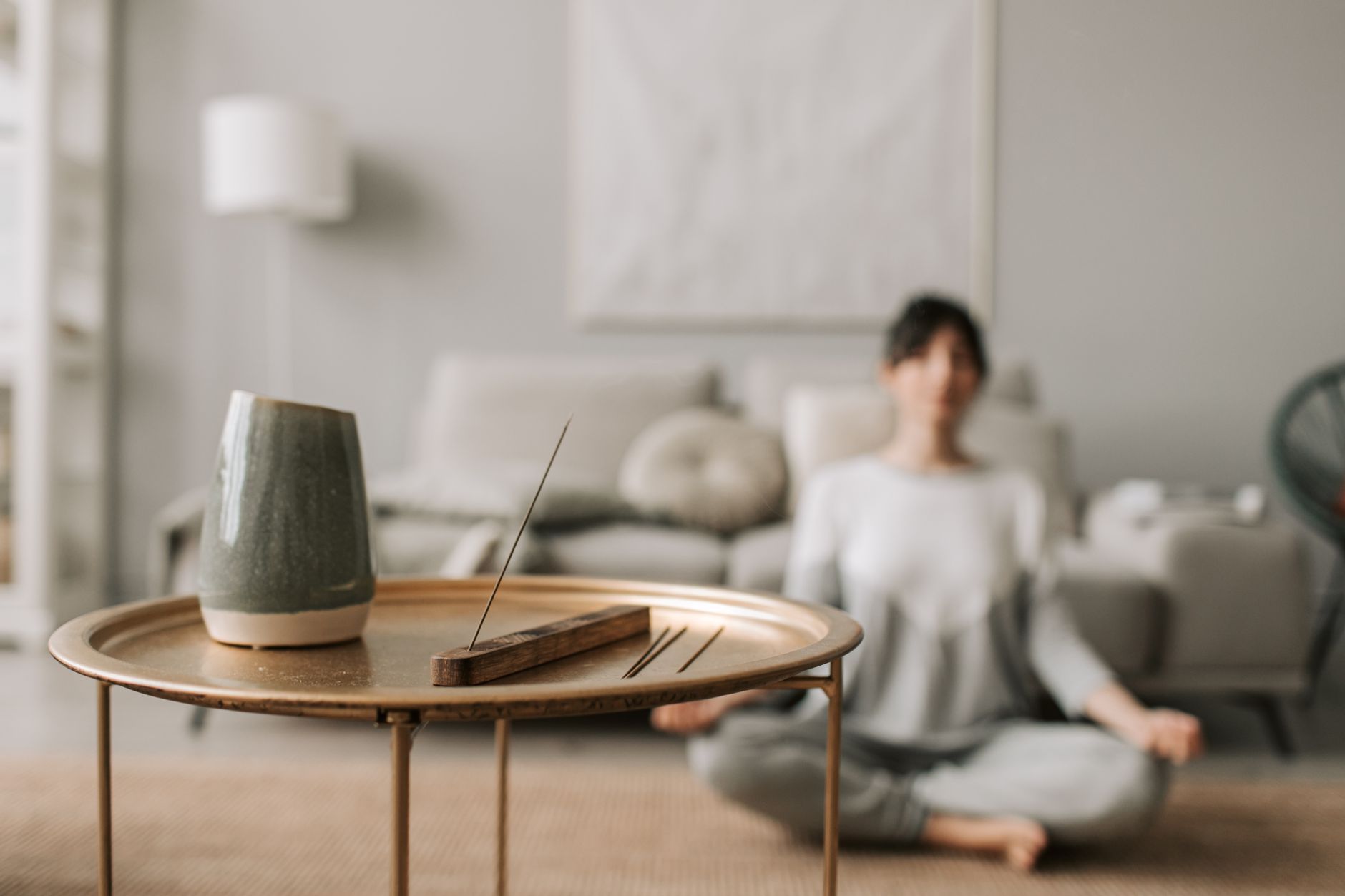Een vrouw mediteert ontspannen in een lichte woonkamer.